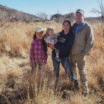 Addie (left) and Jude Schuenemeyer, founders of the Montezuma Orchard Restoration Project, with daugthers, Nora, 8, (far left) and Hazel, one year old, in their orchard, which is also a preserve for natural native grasses in McElmo Canyon near Cortez, Colorado on November 25, 2019. Through their 17-year-old orchard project the Schuenemeyers are preserving the genetic heritage of Colorado's historic orchards. Special to The Colorado Sun/Dean Krakel Good Apple Press / News